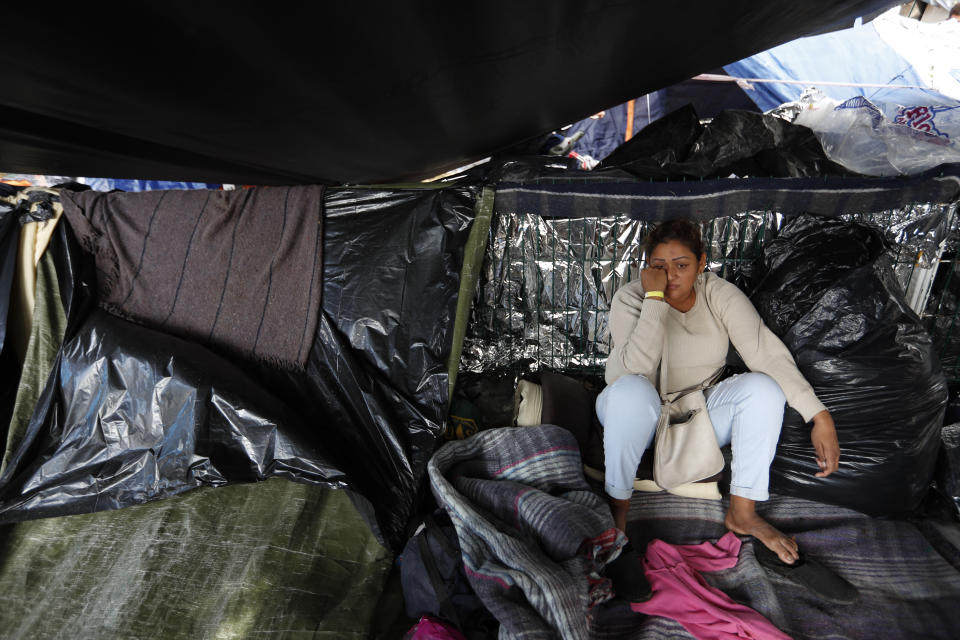 A woman from El Salvador waits to see whether the majority of migrants decide to move, as Central Americans debate individually whether to accept the city's plan to move them to a new shelter from the Benito Juarez sports complex, in Tijuana, Mexico, Friday, Nov. 30, 2018. Authorities in the Mexican city of Tijuana have begun moving some of more than 6,000 Central American migrants from an overcrowded shelter on the border to an events hall further away.(AP Photo/Rebecca Blackwell)