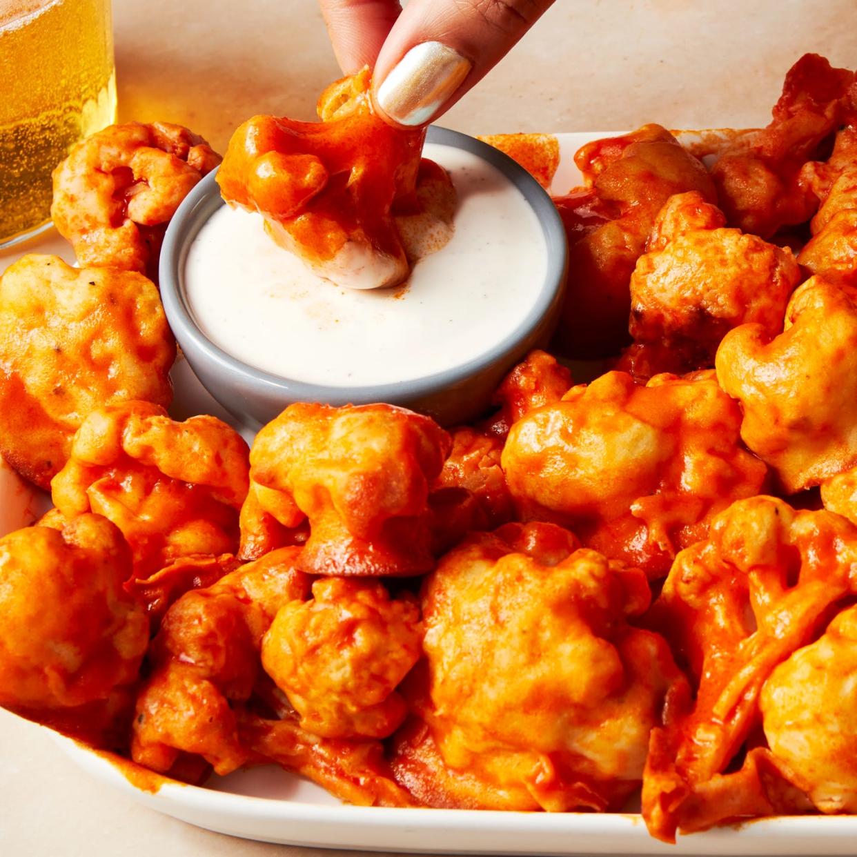 fried cauliflower wings tossed in buffalo sauce on a platter with ranch dressing