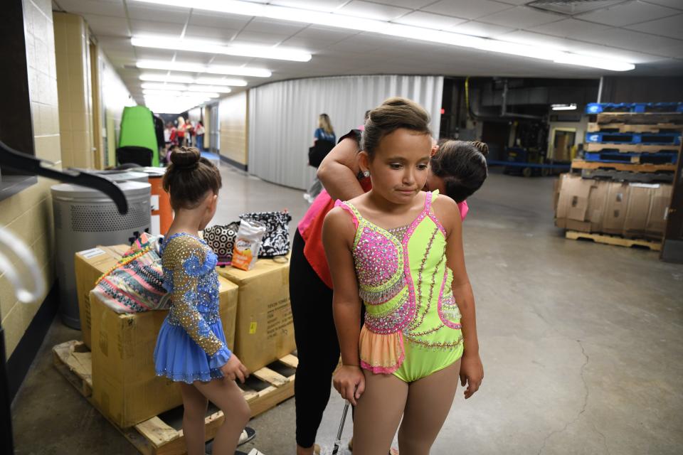 Ashley Dasher, 5, left, waits as Palmer Dasher gets Perry Dasher, 10, into her costume for the annual America's Youth on Parade baton twirling competition at the University of Notre Dame in South Bend on July 25, 2023. They are from Savannah, Ga., and this is not the sisters' first time competing.