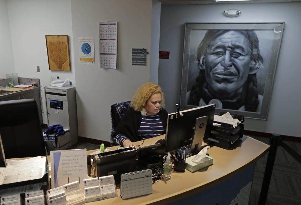 Nia Tagoai, a patient scheduler at a clinic offering health care and other services operated by the Seattle Indian Health Board, works at her desk Friday, Jan. 11, 2019, in Seattle. Fallout from the federal government shutdown is hurting hundreds of Native American tribes and entities that serve them. The pain is especially deep in tribal communities with high rates of poverty and unemployment, and where one person often supports an extended family. (AP Photo/Ted S. Warren)