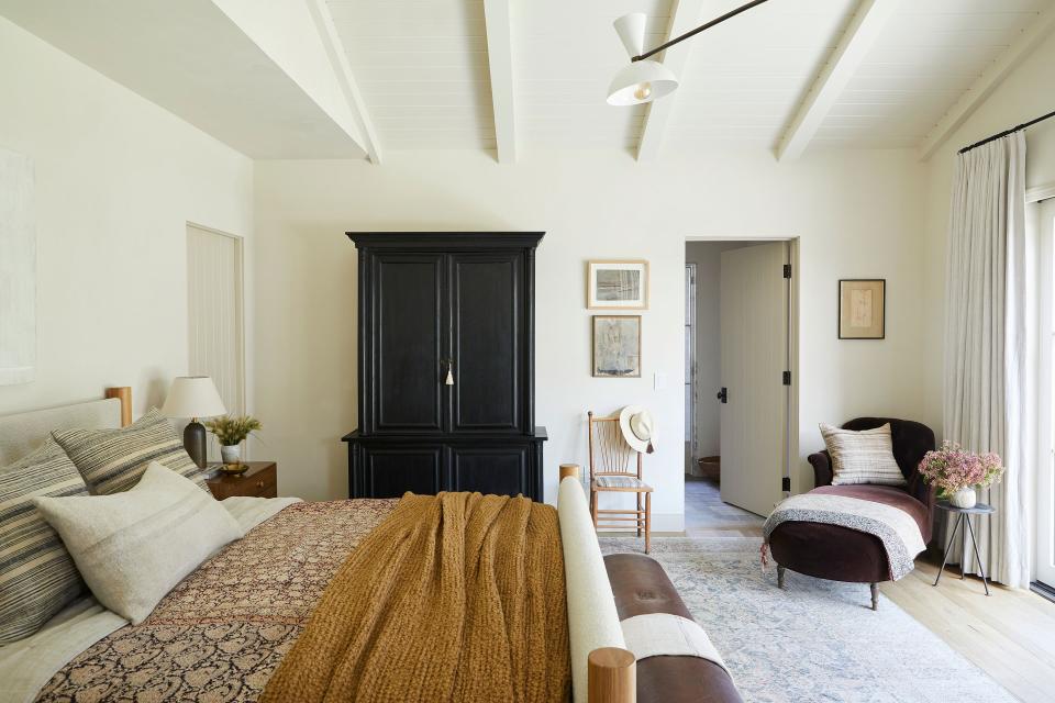 A Jeanette Farrier quilt—hand-stitched from vintage saris by women in Kolkata, India—inspired the shades of black, mustard, and rust used throughout the East-facing main bedroom. “They relate to each other without feeling too match-y,” says Lewis. She also juxtaposed textures with a natural oak and boucle bed from Shoppe Amber Interiors, a vintage leather pommel horse used as a bench, a U.K.-imported vintage wood armoire, and the Milo chaise from Shoppe Amber Interiors in Rogers & Goffigon Redwood velvet.