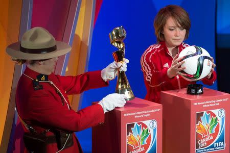 A member of the Royal Canadian Mounted Police carries the FIFA Women's World Cup trophy along with West Ottawa Soccer Club player Talia Laroche, who carries the official match ball, as part of the preliminary activities surrounding the official draw for the FIFA Women's World Cup Canada 2015 in Gatineau, Quebec December 6, 2014. Mandatory Credit: Marc DesRosiers-USA TODAY Sports