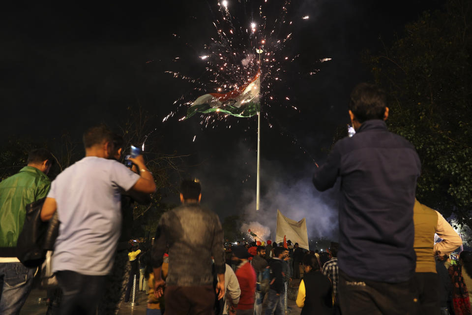 Crackers burst beside a giant Indian national flag as supporters of India's ruling Bhartiya Janata Party celebrate reports of Indian aircrafts bombing Pakistan territory, in New Delhi, India, Tuesday, Feb. 26, 2019. A pre-dawn airstrike inside Pakistan that India said targeted a terrorist training camp and killed a "very large number" of militants ratcheted up tensions on Tuesday between the two nuclear-armed rivals at odds over the disputed territory of Kashmir. (AP Photo/Altaf Qadri)