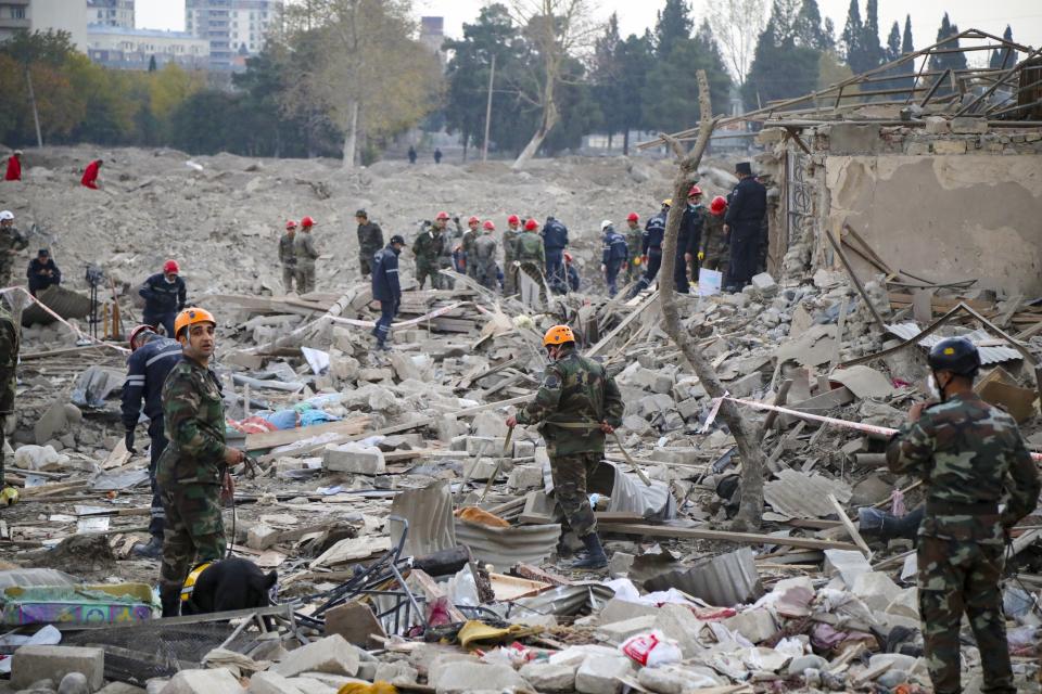 Soldados y bomberos buscan sobrevivientes entre los escombros de una zona residencial atacada con un cohete disparado durante la noche por fuerzas armenias en Ganyá, la segunda ciudad más grande de Azerbaiyán, cerca de la frontera con Armenia, el sábado 17 de octubre de 2020. (AP Foto/Aziz Karimov)