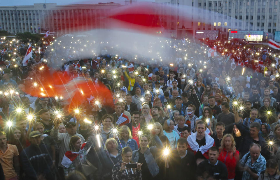 FILE - In this file photo taken on Wednesday, Aug. 19, 2020, Belarusian opposition supporters light phones lights and wave an old Belarusian national flags during a protest rally in front of the government building at Independence Square in Minsk, Belarus. A former Soviet republic on the fault line between Russia and Europe is boiling with revolt this summer. Sounds familiar — but Belarus 2020 isn’t Ukraine 2014, and that’s why it’s hard to predict what will happen next. (AP Photo/Dmitri Lovetsky, File)