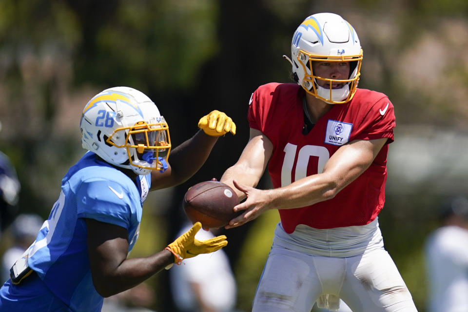 Los Angeles Chargers running back Isaiah Spiller (28) and quarterback Justin Herbert (10) participate in drills during a combined NFL practice with the Dallas Cowboys at the Los Angeles Rams' practice facility in Costa Mesa, Calif. Wednesday, Aug. 17, 2022. (AP Photo/Ashley Landis)