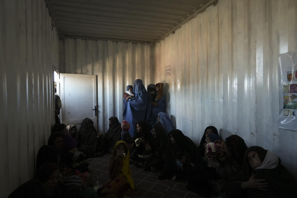 Afghan women wait inside a makeshift clinic organized by World Vision at a settlement near Herat, Afghanistan, Dec. 16, 2021. The aid-dependent country’s economy was already teetering when the Taliban seized power in mid-August amid a chaotic withdrawal of U.S. and NATO troops. The consequences have been devastating for a country battered by four decades of war, a punishing drought and the coronavirus pandemic. (AP Photo/Mstyslav Chernov)