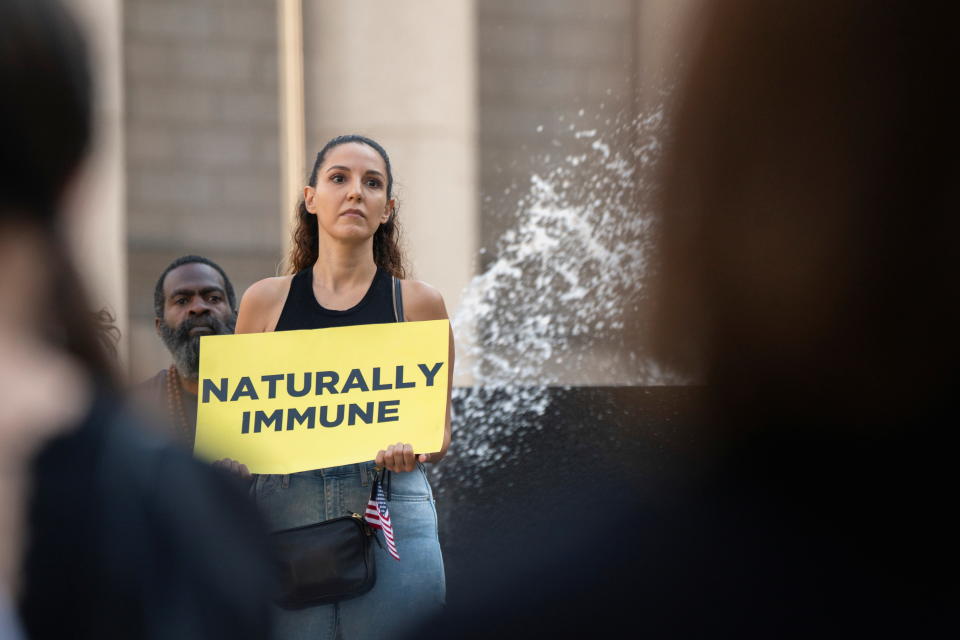 A person holds a sign during a protest against mandated coronavirus disease