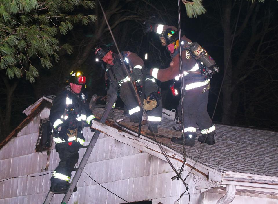 Stoughton firefighters break off sections of the roof of a house at 40 Holbrook Ave., looking for hot spots and smoke from within the roof and walls on Wednesday, Feb. 1, 2023.