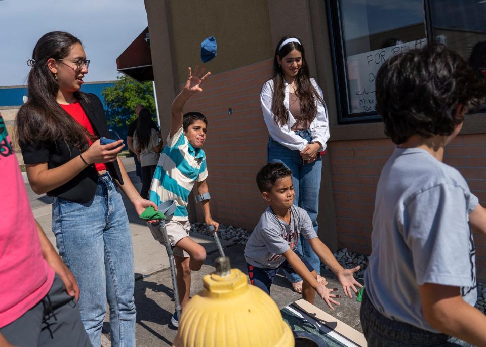 Saleh Humaid, 8, of Gaza, tosses a bean bag while playing a game of cornhole with Jenna Saker, right, of Dearborn Heights, and Dania Jadallah, left, of Dearborn, as Ryan Elabed, of Dearborn, catches an incoming bag during a community meet and greet with Saleh at the Hanini Outreach and Community Center in Dearborn on Sunday, June 25, 2023, put on by the Palestine Children's Relief Fund's Detroit chapter.