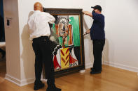 From left, Jose Reynoso and Terence McAllister lift a still life painting by Pablo Picasso titled "Buste d'Homme" at the Bellagio Gallery of Fine Art Tuesday, Oct. 19, 2021 in Las Vegas. The artworks — nine are paintings and two are ceramic pieces — are part of MGM Resorts' collection and will be offered at auction Saturday. (Wade Vandervort/Las Vegas Sun via AP)