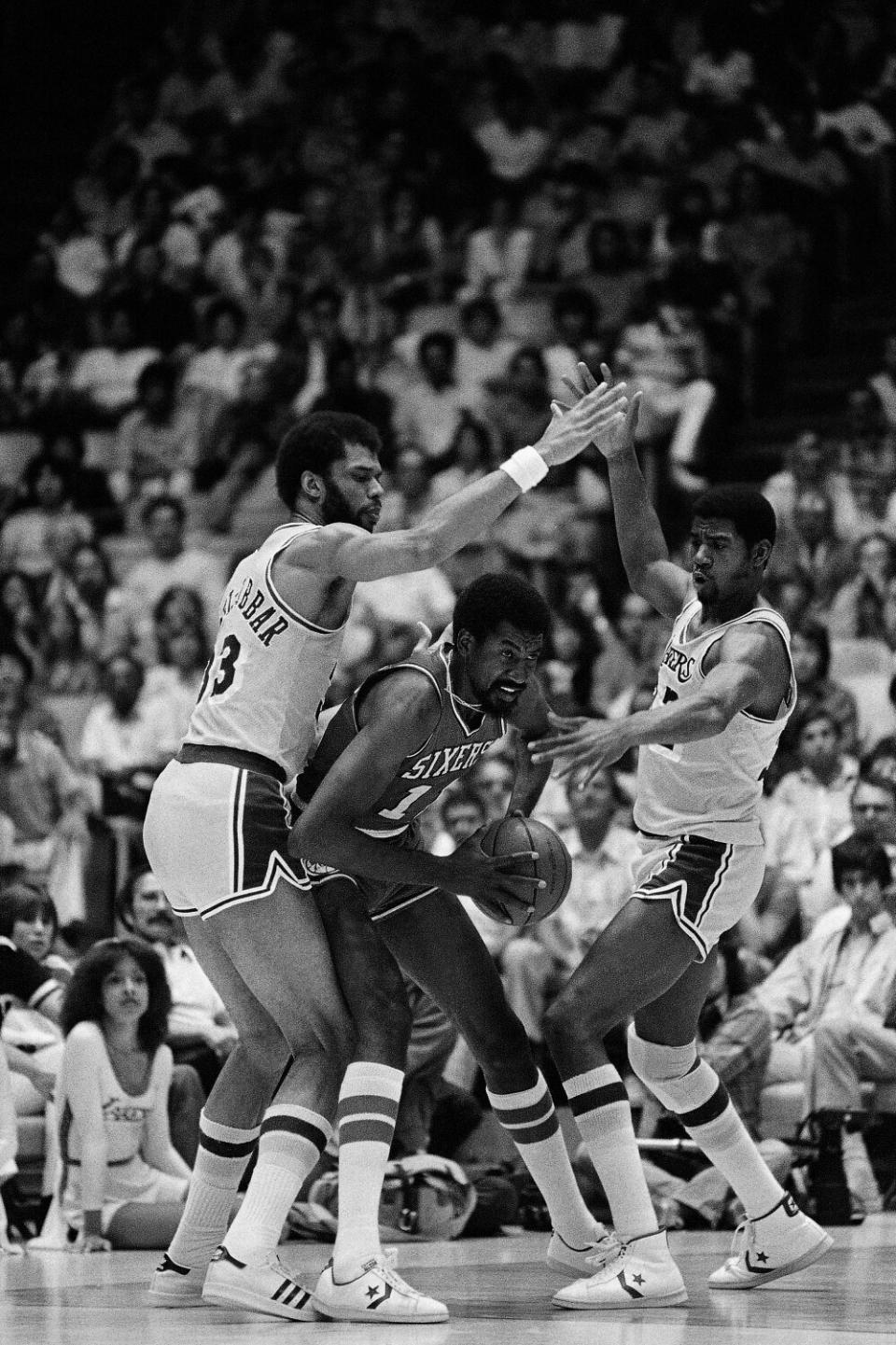 Lakers stars Kareem Abdul-Jabbar, left, and Magic Johnson defend against Philadelphia 76ers forward Caldwell Jones.