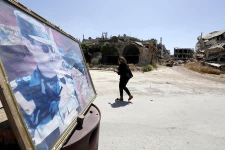 A woman walks past a poster depicting Syria's President Bashar al-Assad in the old city of Homs June 3, 2015. REUTERS/Omar Sanadiki/Files