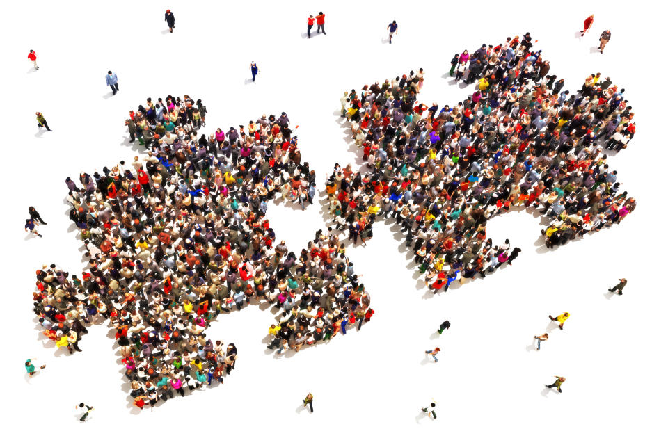 Aerial view of two large puzzle pieces made up of standing people.