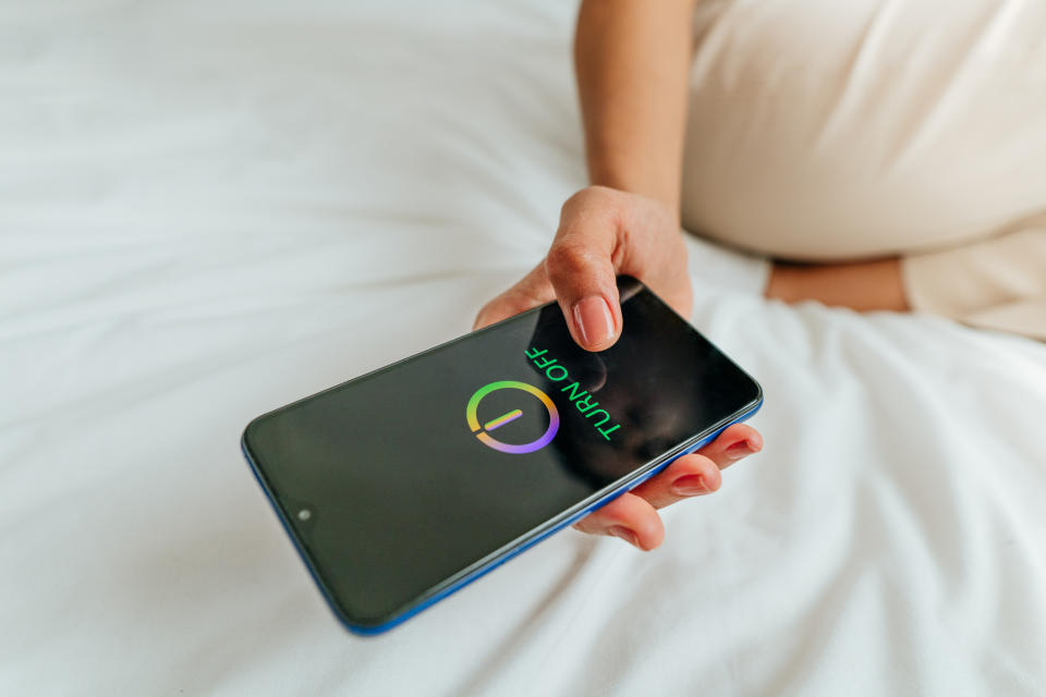 Primer plano de mano femenina apagando el smartphone. (Getty Creative)