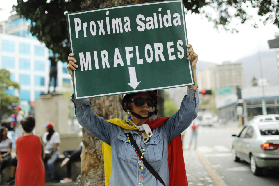An opponent to Venezuela's President Nicolas Maduro holds a sign reading in Spanish "Next exit, Miraflores", in reference to the Miraflores presidential palace, during a march in Caracas, Venezuela, Saturday, May 4, 2019. Opposition leader Juan Guaido took his quest to win over Venezuela's troops back to the streets calling his supporters to participate in a mobilization outside military installations around the country. (AP Photo/Ariana Cubillos)