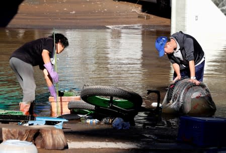 People clean up debris in a flooded residential area due to Typhoon Hagibis, in Kawasaki, Japan