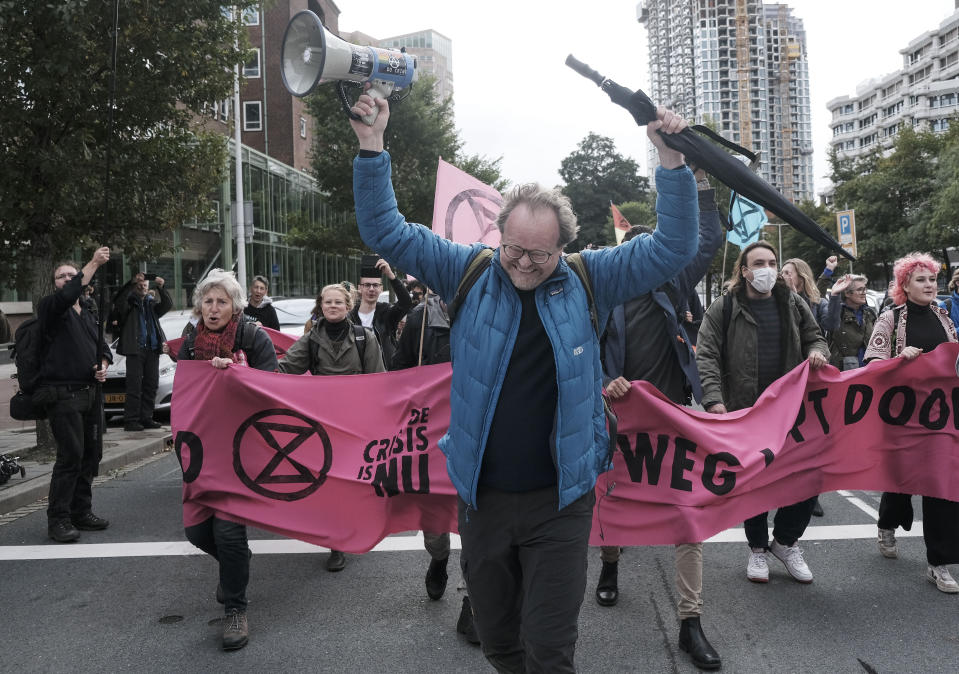 Protestors from climate activism group of Extinction Rebellion block a busy intersection near the temporary home of the Dutch parliament in The Hague, Netherlands, Monday, Oct. 11, 2021. The group says it plans a series of demonstrations in the city throughout the week ahead of a major United Nations climate conference that opens Oct. 31, in Glasgow. (AP Photo/Patrick Post)