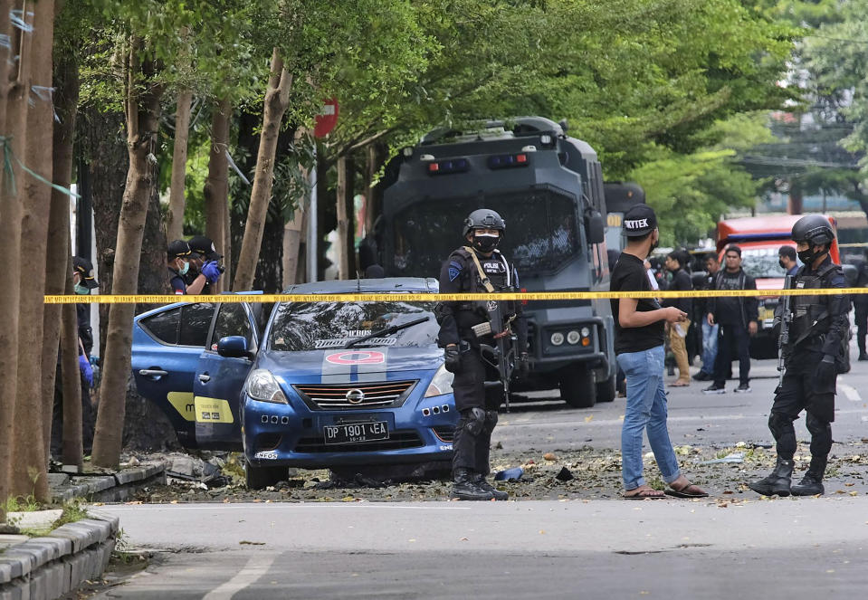Police officers inspect the area outside the church where an explosion went off in Makassar, South Sulawesi, Indonesia, Sunday, March 28, 2021. A suicide bomber blew himself up outside a packed Roman Catholic cathedral on Indonesia's Sulawesi island during a Palm Sunday Mass, wounding a number of people, police said. (AP Photo/Masyudi S. Firmansyah)