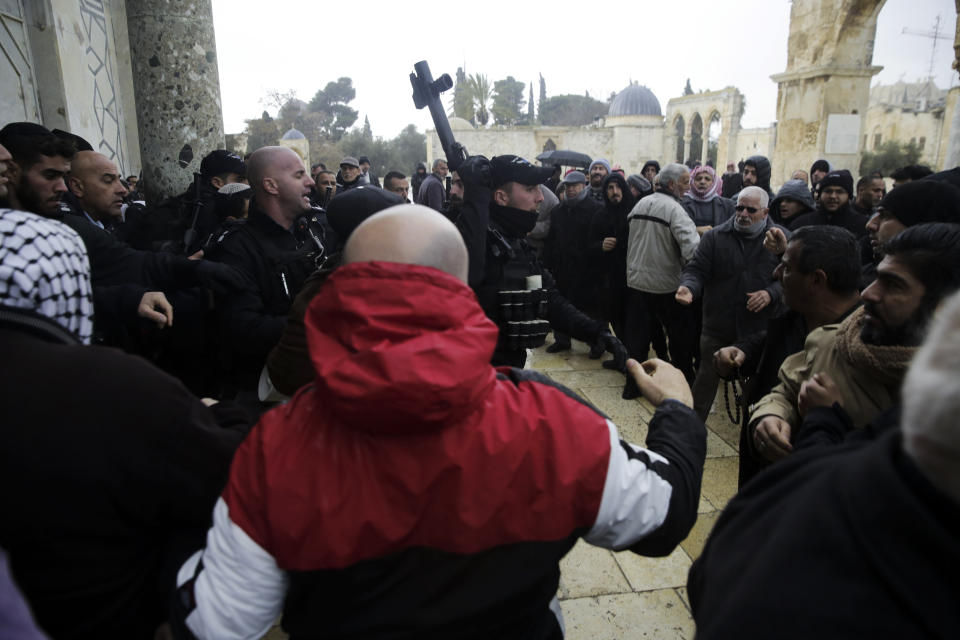 Israeli police stands at the door to the Dome of the Rock mosque confronted by Palestinians, Monday, Jan. 14, 2019. Scuffles broke out at the Dome of the Rock in Jerusalem's Old City on Monday after guards at the mosque refused to allow an Israeli policeman to enter for a routine security check because he was wearing a Jewish skullcap known as a kippah. (AP Photo/Mahmoud Illean)