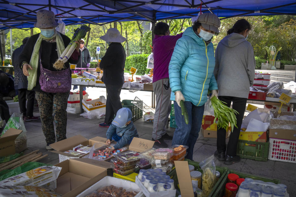 People wearing face masks shop for fresh vegetables at a pop-up market in Beijing, Thursday, April 28, 2022. Beijing shifted more classes online Thursday in a further tightening of COVID-19 restrictions, as China's capital seeks to prevent a wider outbreak. (AP Photo/Mark Schiefelbein)