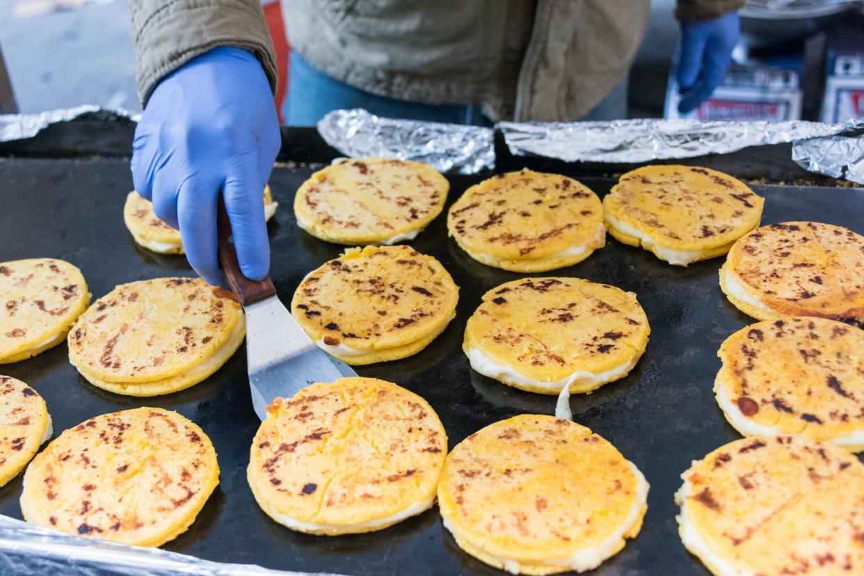 arepas being cooked on street grill