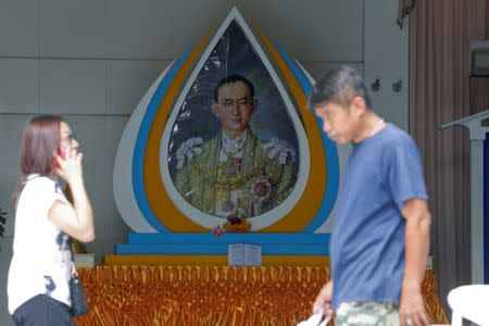 People walk past a picture of Thailand's King Bhumibol Adulyadej at Siriraj Hospital in Bangkok, Thailand, October 10, 2016. REUTERS/Chaiwat Subprasom