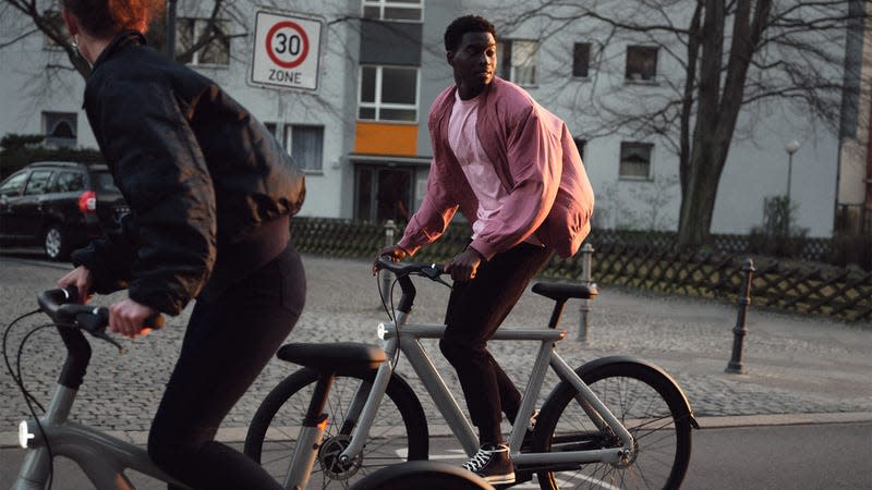 A man wearing a pink shirt rides a Van Moof ebike