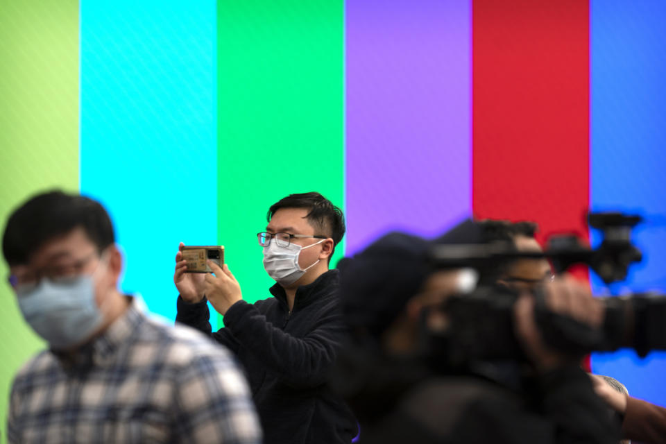 A journalist takes a smartphone photo before a remote video press conference by Chinese Foreign Minister Wang Yi held on the sidelines of the annual meeting of China's National People's Congress (NPC) in Beijing, Sunday, March 7, 2021. (AP Photo/Mark Schiefelbein)