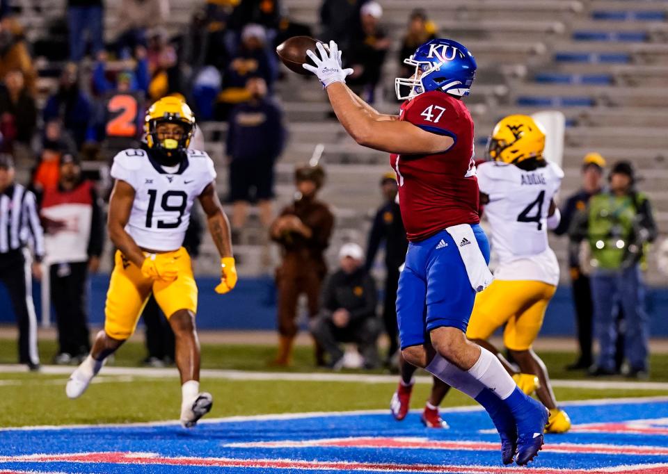 Nov 27, 2021; Lawrence, Kansas, USA; Kansas Jayhawks fullback Jared Casey (47) catches a touchdown pass as West Virginia Mountaineers safety Scottie Young (19) defends during the first half at David Booth Kansas Memorial Stadium. Mandatory Credit: Jay Biggerstaff-USA TODAY Sports