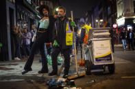 A woman poses with a street cleaner in Soho as late-night drinkers continue into the early hours of Sunday morning as coronavirus lockdown restrictions are eased across England, Sunday July 5, 2020. (Victoria Jones/PA via AP)
