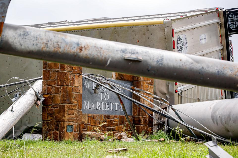 Debris covers a “Welcome to Marietta” sign on Monday after a storm ripped through Marietta on Sunday.