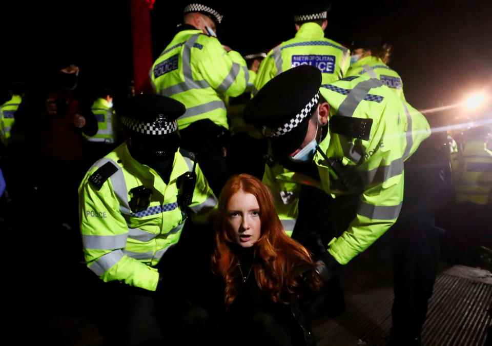 Police detain a woman as people gather at a memorial site in Clapham Common Bandstand, following the kidnap and murder of Sarah Everard, in London, Britain March 13, 2021. REUTERS/Hannah McKay     TPX IMAGES OF THE DAY