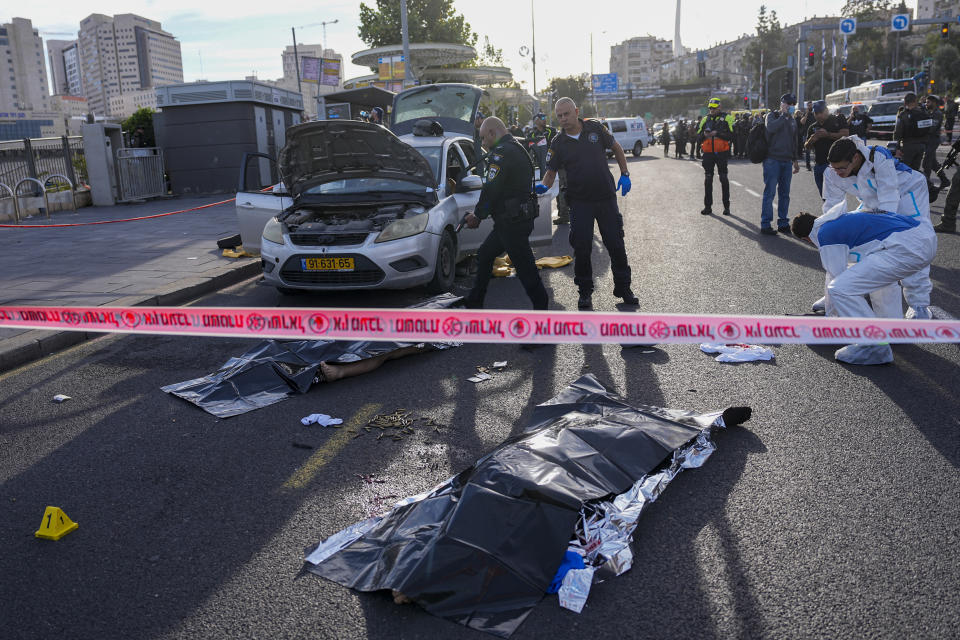 An Israeli police officer aims his firearm at the body of a gunman involved in a shooting attack in Jerusalem, Thursday, Nov. 30, 2023. Two gunman opened fire on a crowded bus station at the entrance of Jerusalem, killing people and wounding others, according to Jerusalem police. (AP Photo/Ohad Zwigenberg)