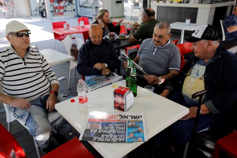 Israeli men sit in a coffee shop next to a local daily newspaper in Ashkelon