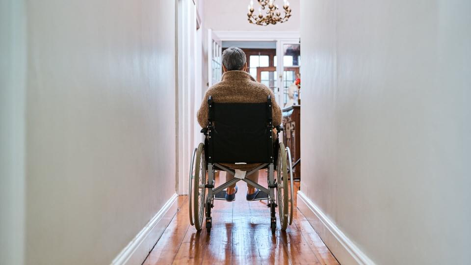 Rearview shot of a senior woman sitting in her wheelchair at home.