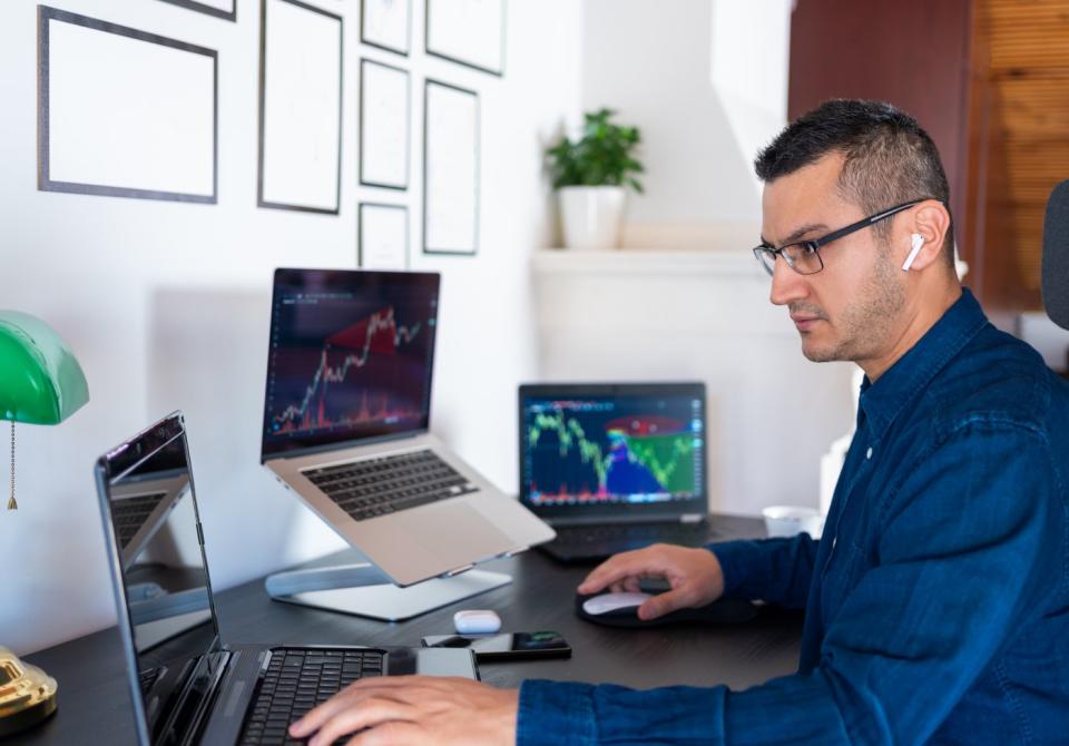 A person is sitting at a desk with multiple computers in front of them.