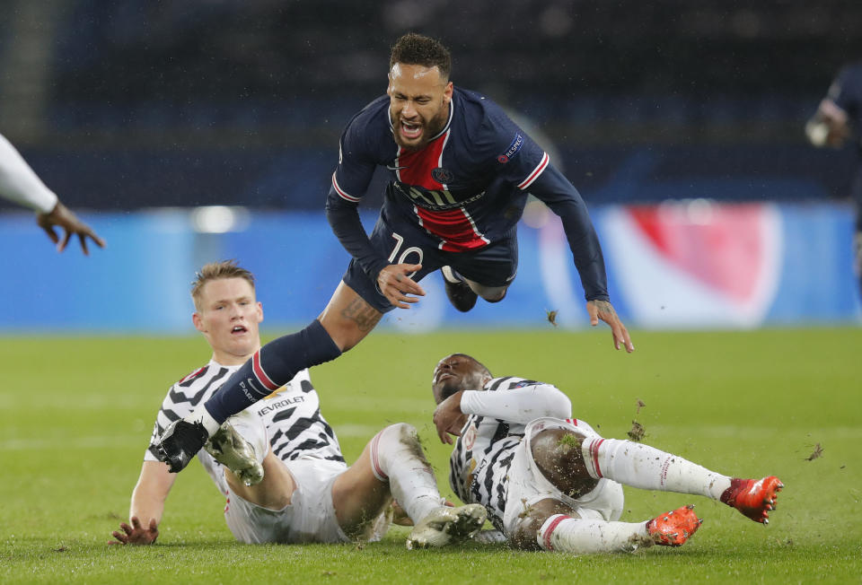 El delantero del PSG Neymar cae ante la marca Aaron Wan-Bissaka (derecha) y Scott McTominay del Manchester United durante el partido por la Liga de Campeones, el martes 20 de octubre de 2020. (AP Foto/Michel Euler)