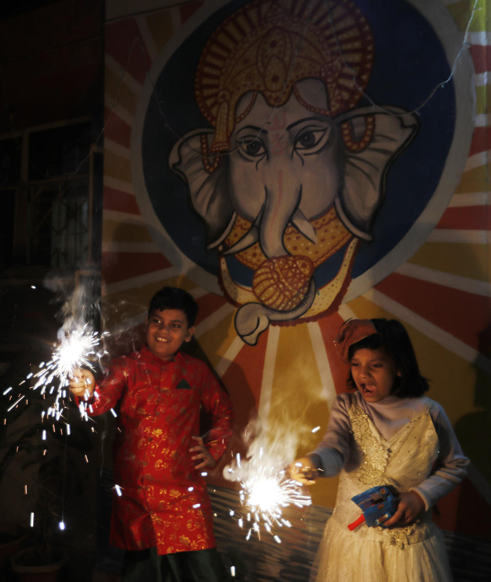 Children play with fireworks during Diwali, the Hindu festival of lights, in Prayagraj, India, Saturday, Nov. 14, 2020. Hindus across the country are celebrating Diwali where people decorate their homes with lights and burst fireworks. (AP Photo/Rajesh Kumar Singh)