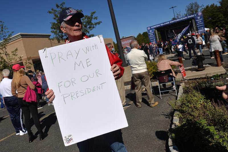 A man holds a sign asking for people to pray with him for President Donald Trump who announced he tested COVID-19 the previous day, at a pro-Trump “New York Triumph” rally, organised by the Staten Island Republican Party, held at Bricktown Center At Charleston in the New York City borough of Staten Island, NY.