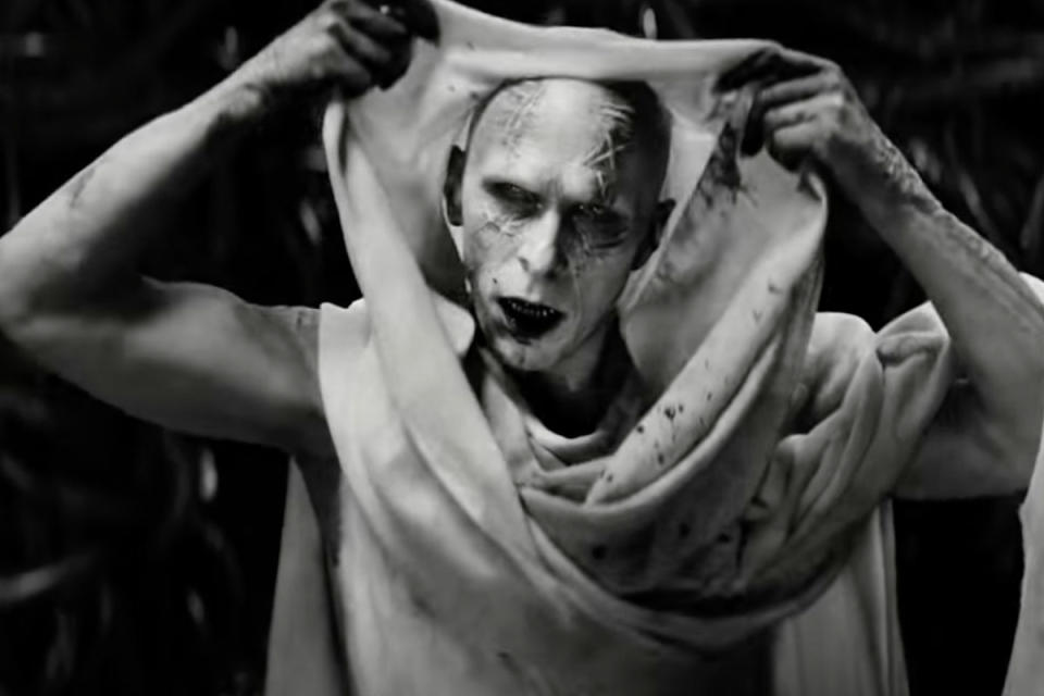 Christian Bale as Gorr the God Butcher, pulling fabric down to reveal his face, in Thor.