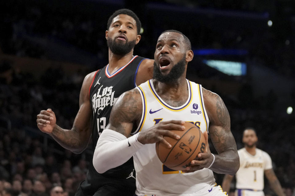 Los Angeles Lakers forward LeBron James, front right, drives to the basket against Los Angeles Clippers forward Paul George (13) during the first half of an NBA basketball game in Los Angeles, Sunday, Jan. 7, 2024. (AP Photo/Eric Thayer)