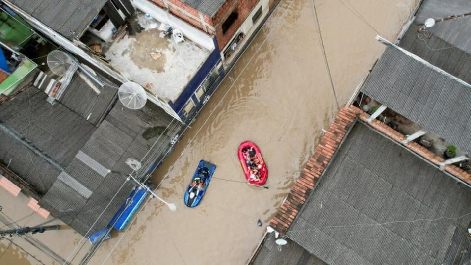 Foto a&#xe9;rea mostra rio inundando e botes resgatando pessoas