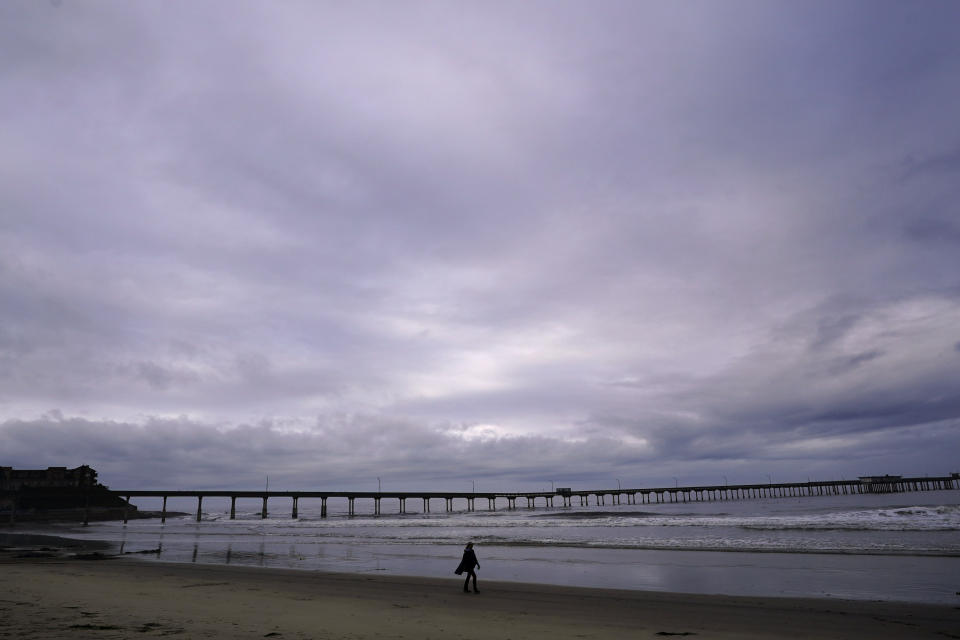 A woman walks along the beach after the passing of Tropical Storm Hilary, Monday, Aug. 21, 2023, in San Diego. (AP Photo/Gregory Bull)