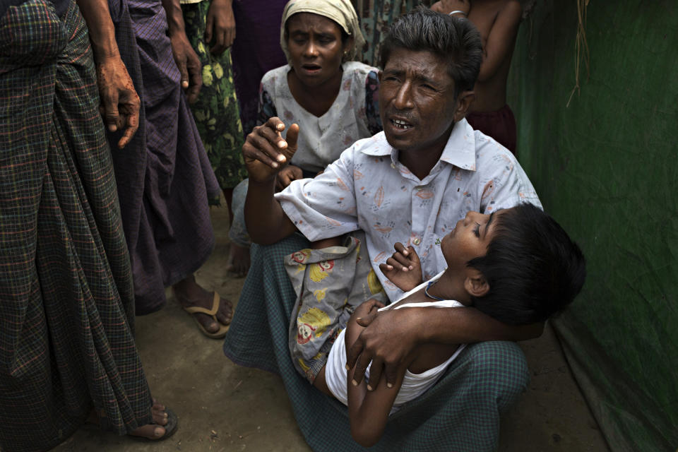 SITTWE, BURMA - MAY 06: Roshida Moud, 12, is held by his father as he explains that his son was hit in the head with a stone during the Rakhine violence in 2012. Roshida Moud has been unable to function by himself since the inury.150,000 Rohingya IDP (internally displaced people) are currently imprisoned in refugee camps outside of Sittwe in Rakhine State in Western Myanmar. Medecins Sans Frontieres (MSF), the primary supplier of medical care within the camps, was banned in March by the Myanmar government. Follow up attacks by Buddhist mobs on the homes of aid workers in Sittwe put an end to NGO operations in the camps. Though some NGOs are beginning to resume work, MSF remains banned, and little to no healthcare is being provided to most Rohingya IDPs. One Rohingya doctor is servicing 150,000 refugees with limited medication. Several Rakhine volunteer doctors sporadically enter the camps for two hours a day. Births are the most complicated procedures successfully carried out in the camps, requests to visit Yangon or Sittwe hospitals for life threatening situations require lengthy applications and are routinely denied. Malnutrition and diarrhea are the most widespread issues, but more serious diseases like tuberculosis are going untreated and could lead to the rise of drug resistant tuberculosis (DR-TB).  (Photo by Andre Malerba/Getty Images)