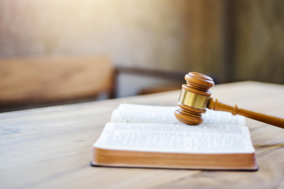 Close up of Judge's gavel on an open bible with Blurred page on a wooden table. Christian background show God justice and Christ's redemption  concept