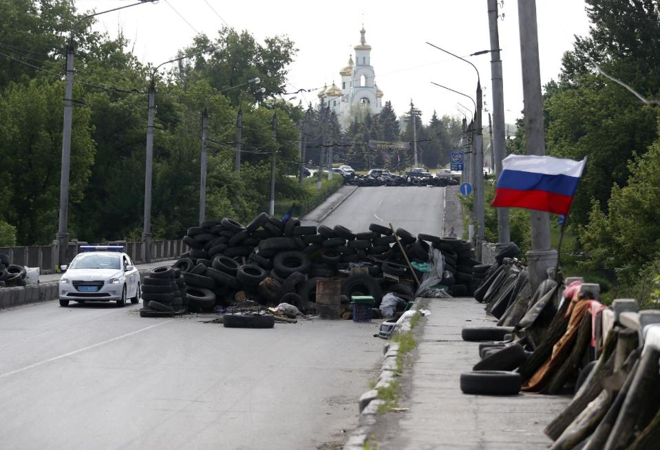 A car passes by the barricades with a Russian national flag on a road leading into Slovyansk, eastern Ukraine, Tuesday, May 13, 2014. Pro-Russian insurgents, who have seized government buildings and clashed with government forces during the past month, held Sunday's referendum, which Ukraine's acting president called a "sham" and Western governments said violated international law. (AP Photo/Darko Vojinovic)