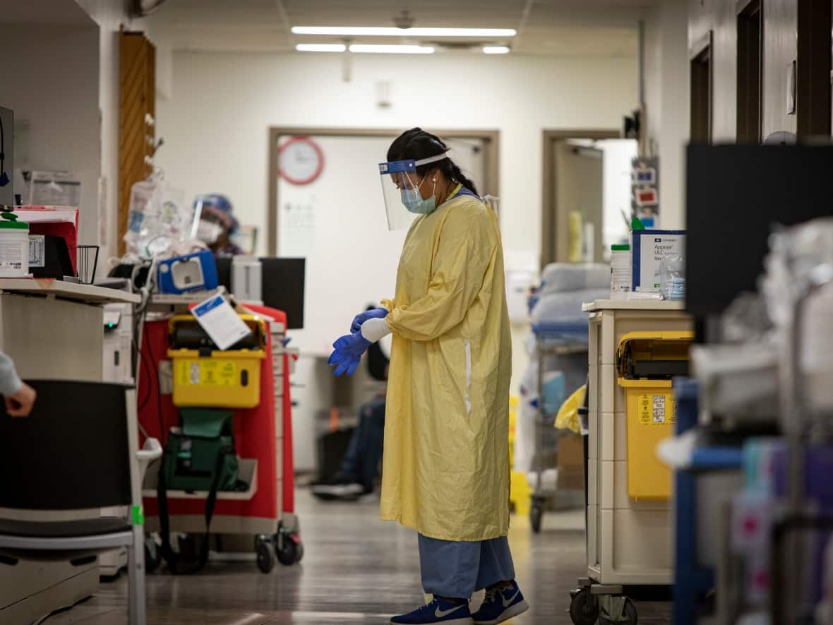 A nurse wearing personal protective equipment prepares to treat a patient in the emergency department at Scarborough General Hospital last April. (Evan Mitsui/CBC - image credit)