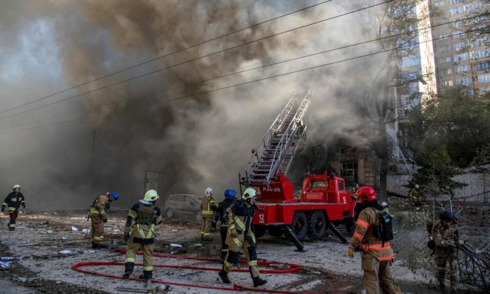 Firefighters help a local woman evacuate from a residential building destroyed by a Russian drone strike in Kyiv.