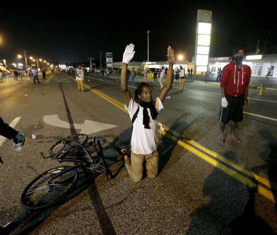 <p>A man holds his hands up in the street after a standoff with police Monday, Aug. 18, 2014, during a protest for Michael Brown, who was killed by a police officer Aug. 9 in Ferguson, Mo. (Charlie Riedel/AP) </p>